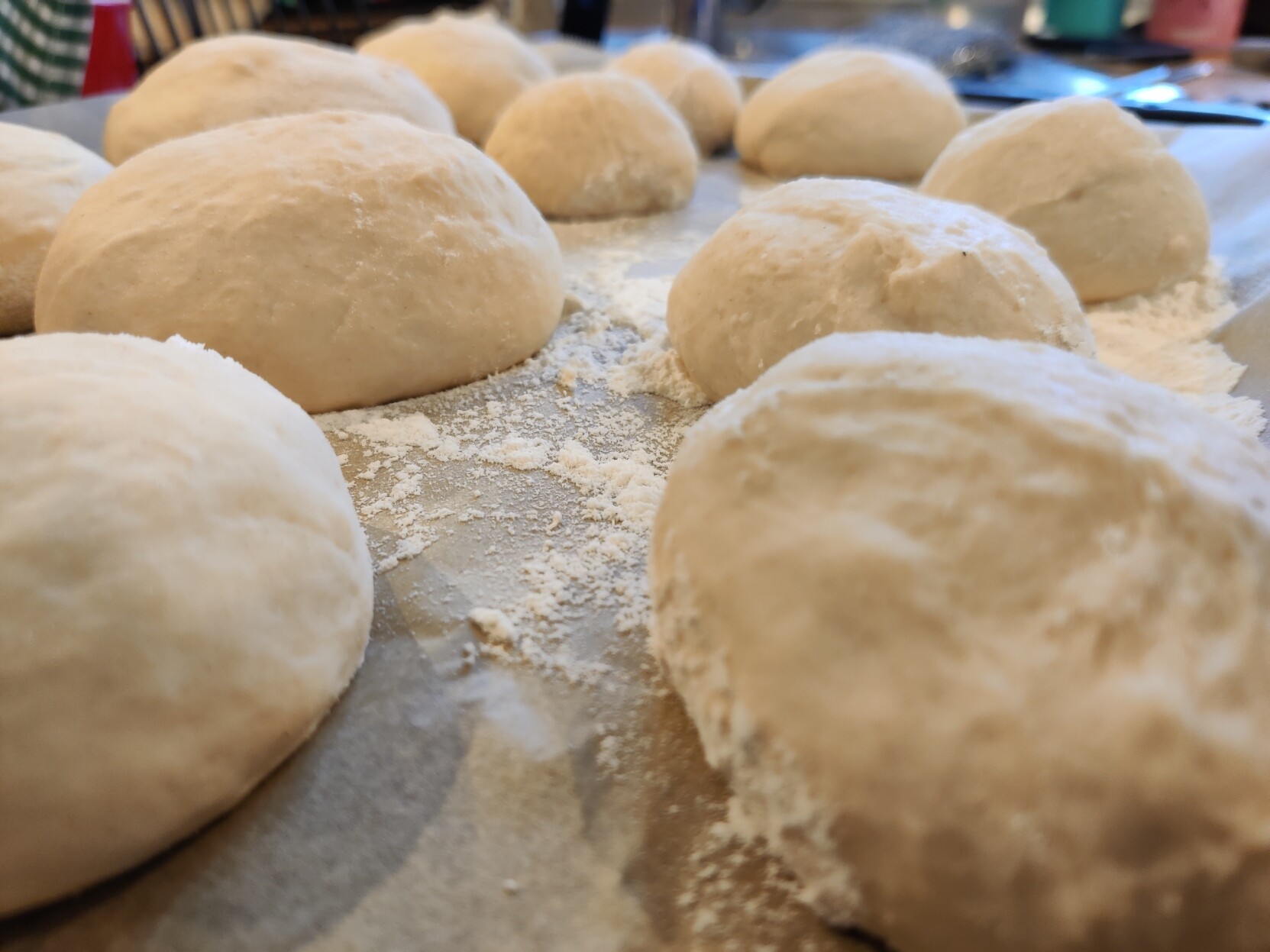A baking tray full of dough balls, some of them already risen some of them still pretty gnarly