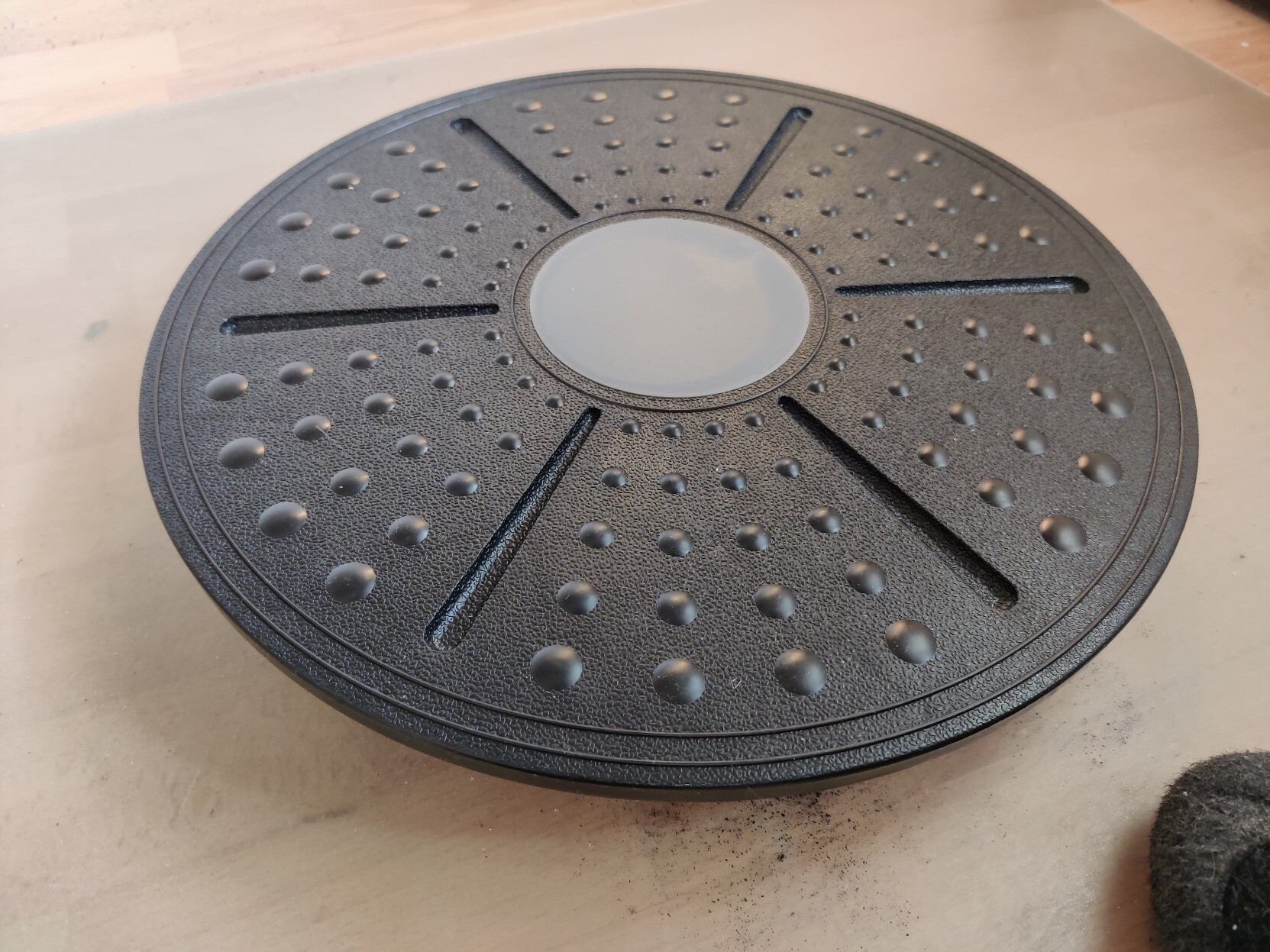 Eine runde Scheibe aus grauem Plastik mit Noppen, die auf dem Boden steht. Die Noppen sind kreisrund um die Mitte herum aufgebracht. Die Scheibe ist ca 40cm im Durchmesser und steht nur auf einem runden Punkt in der Mitte.