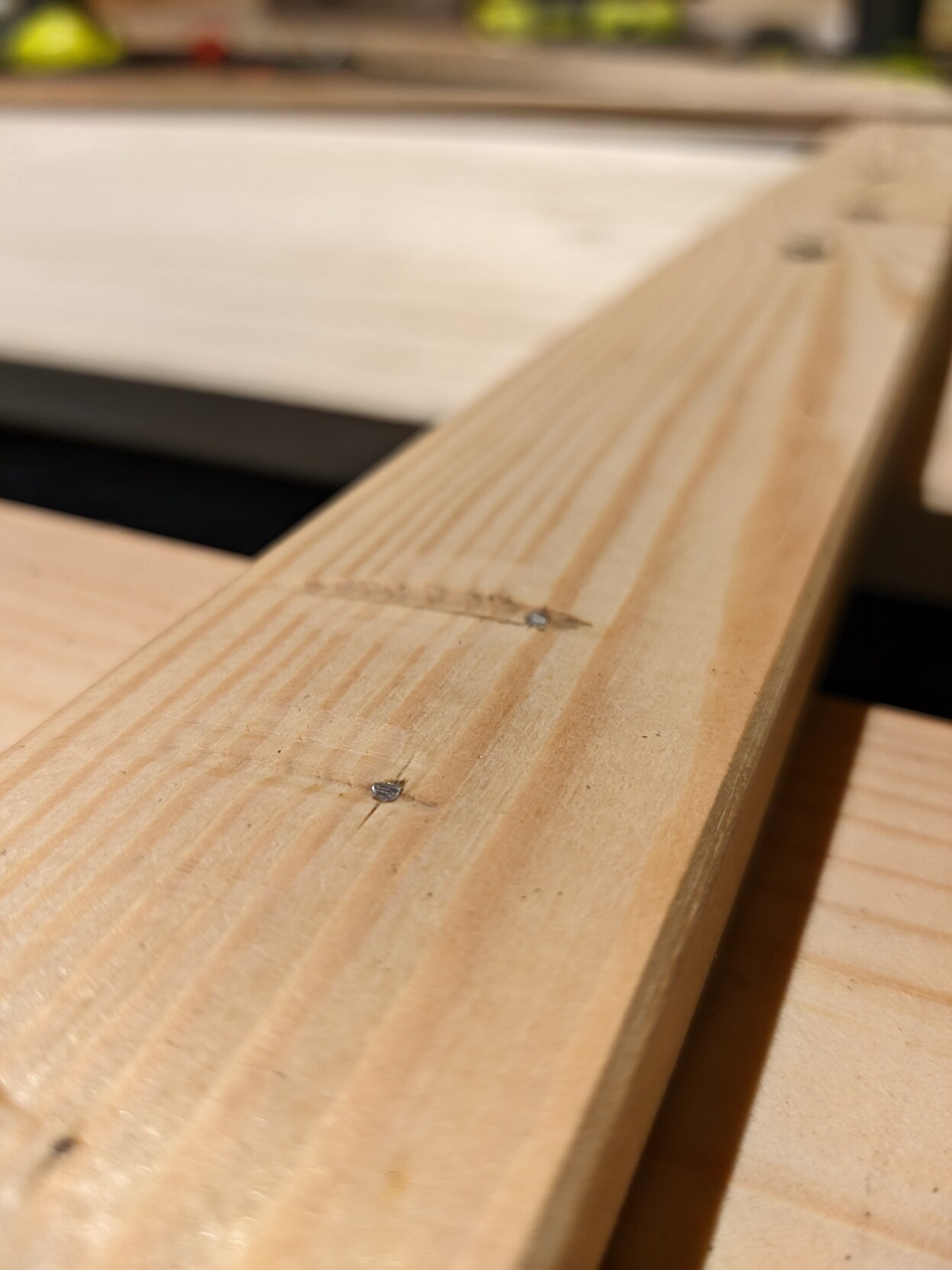 Eine Holzleiste mit abgeschliffen Schrauben die von der Gegenseite aus durchgedreht wurden