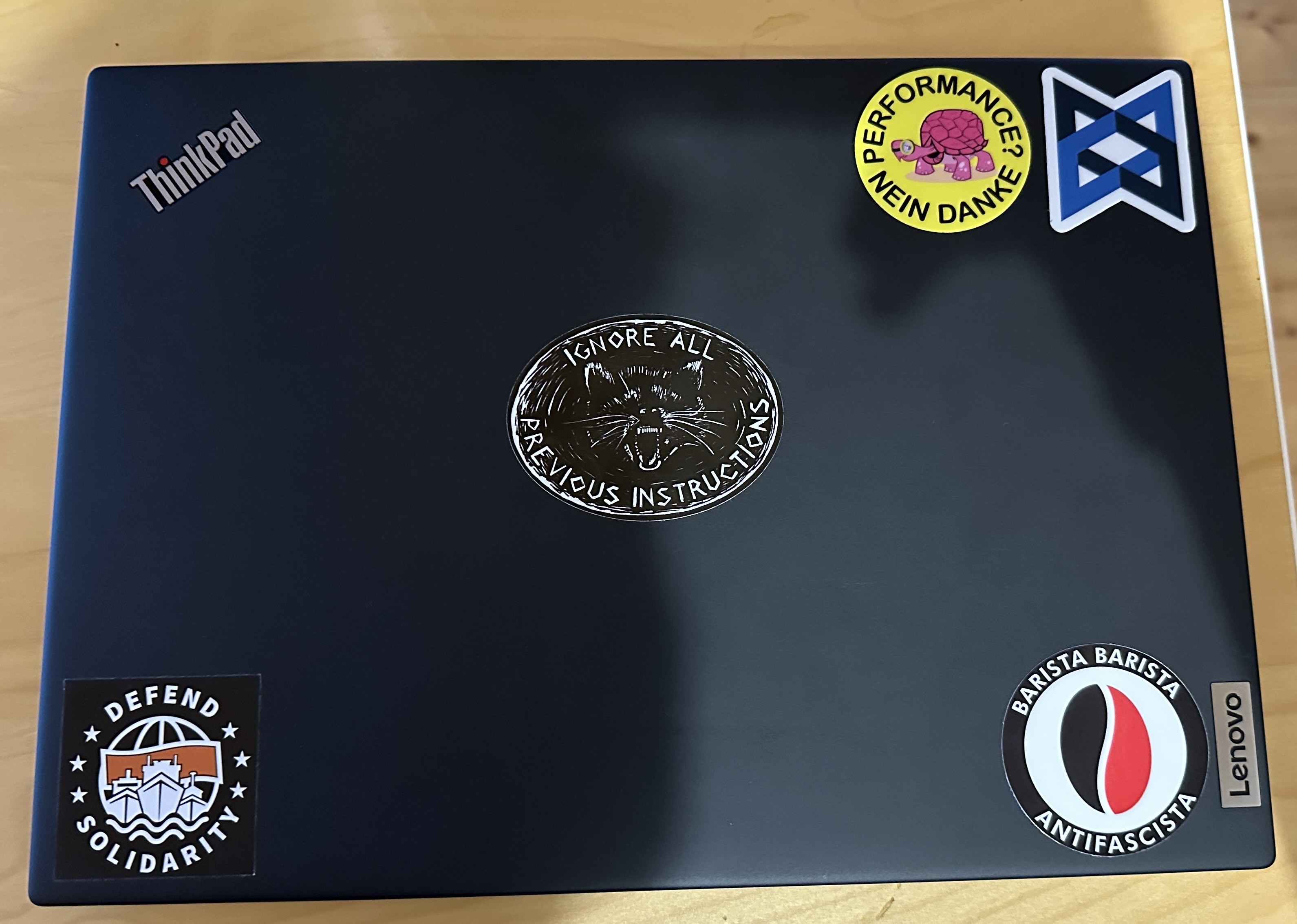 A Thinkpad with stickers: „Ignore all previous instructions“, „Performance? No thanks“, a Backbone logo, „Defend Solidarity“ from sea watch and „Barista Barista Antifacista“
